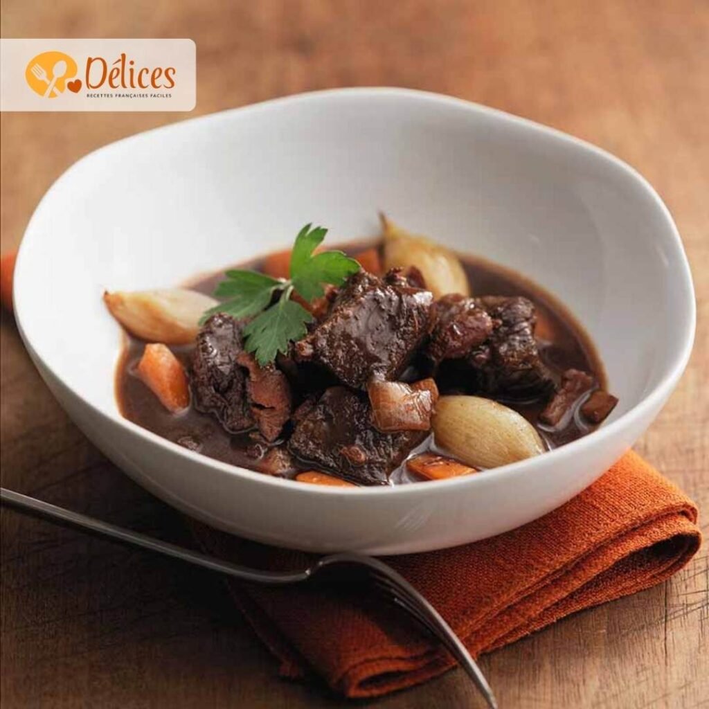 Gros plan sur un bol de ragoût de bœuf bourguignon sans vin, montrant des morceaux de bœuf, des oignons et des carottes en sauce brune foncée. Le plat est garni de persil.