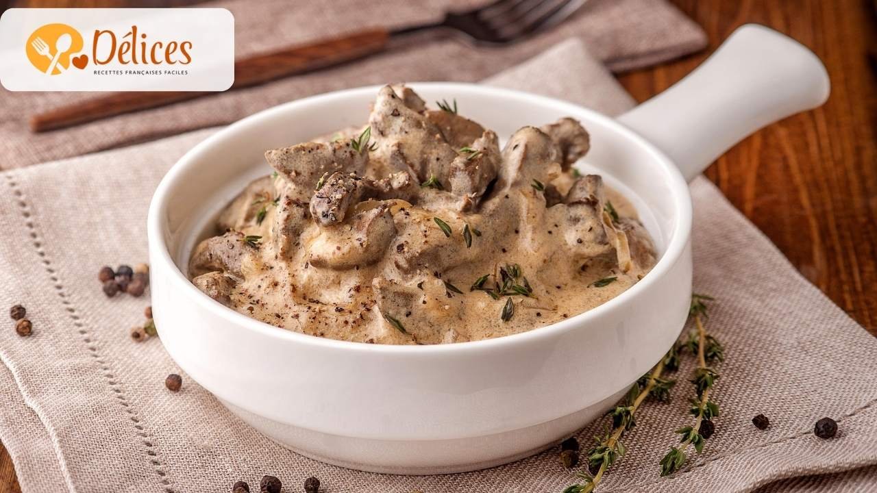 Gros plan sur un plat de bœuf Stroganoff garni de thym, avec des morceaux de bœuf et des champignons dans une sauce à la crème moutardée.