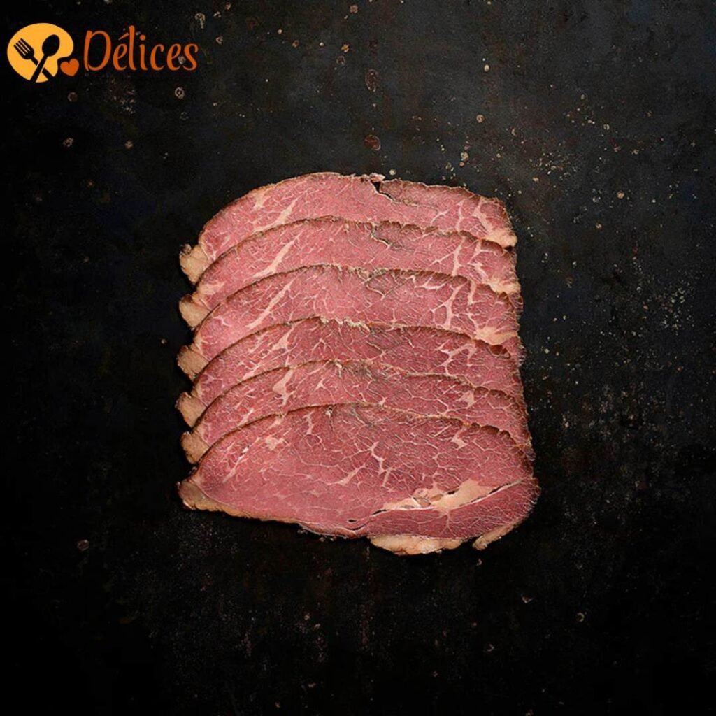 Pile de tranches fines de pastrami de bœuf, avec une bordure foncée d'épices, sur un fond sombre. Image du Pastrami de qualité.