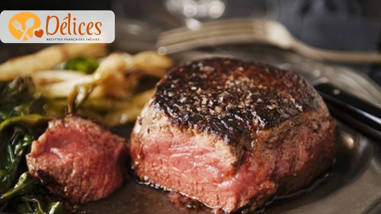 Gros plan sur un morceau épais de pavé de bœuf cuit et tranché, montrant une cuisson rosé (saignante), servi avec une garniture de légumes verts et assaisonné de gros sel.