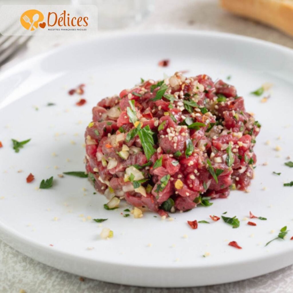 Tartare de bœuf haché et assaisonné, formant une belle quenelle sur une assiette blanche.
