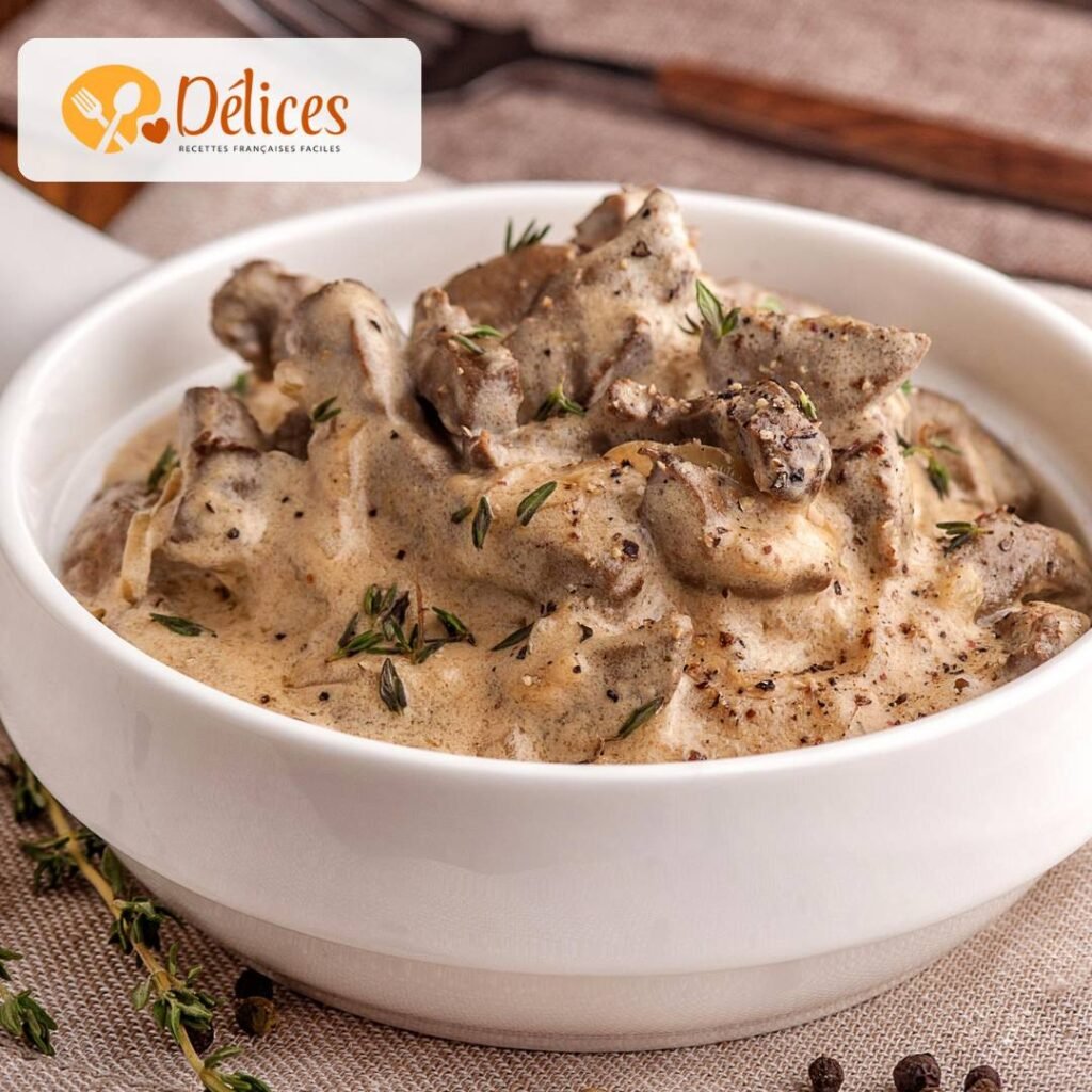 Gros plan sur un bol blanc rempli de Stroganoff, un plat de lanières de viande et de champignons dans une sauce à la crème épaisse et garni de thym frais. Image de la recette stroganoff facile.