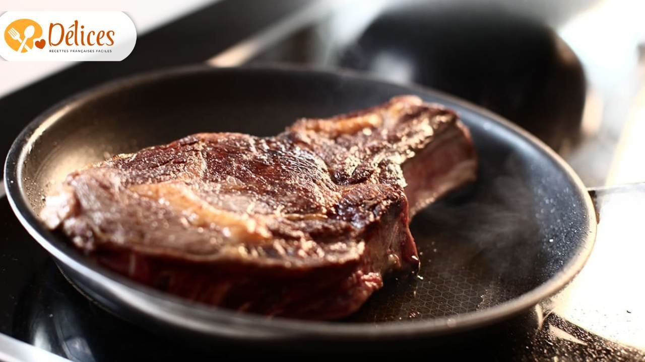 Épaisse Côte de Bœuf à la poêle en train de griller, montrant une croûte caramélisée et de la vapeur de cuisson. Photo illustrant la technique de saisie d'une côte de bœuf.