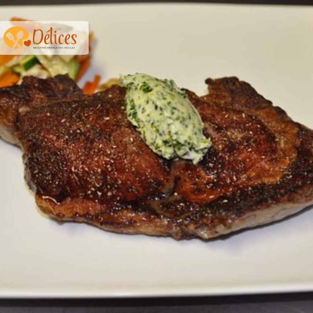 Steak de faux filet de bœuf cuit, de couleur brun foncé, sur une assiette blanche avec une noix de beurre aux herbes. Photo illustrant la recette de faux filet.