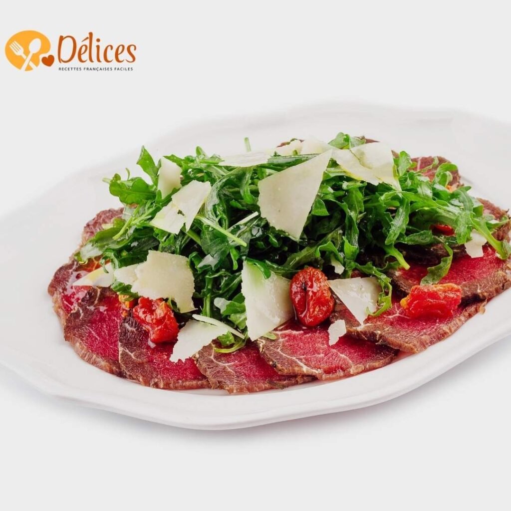 Gros plan d'une assiette de Carpaccio de Bœuf avec fines tranches de bœuf cru, recouvertes de roquette, de copeaux de parmesan et de tomates séchées.
