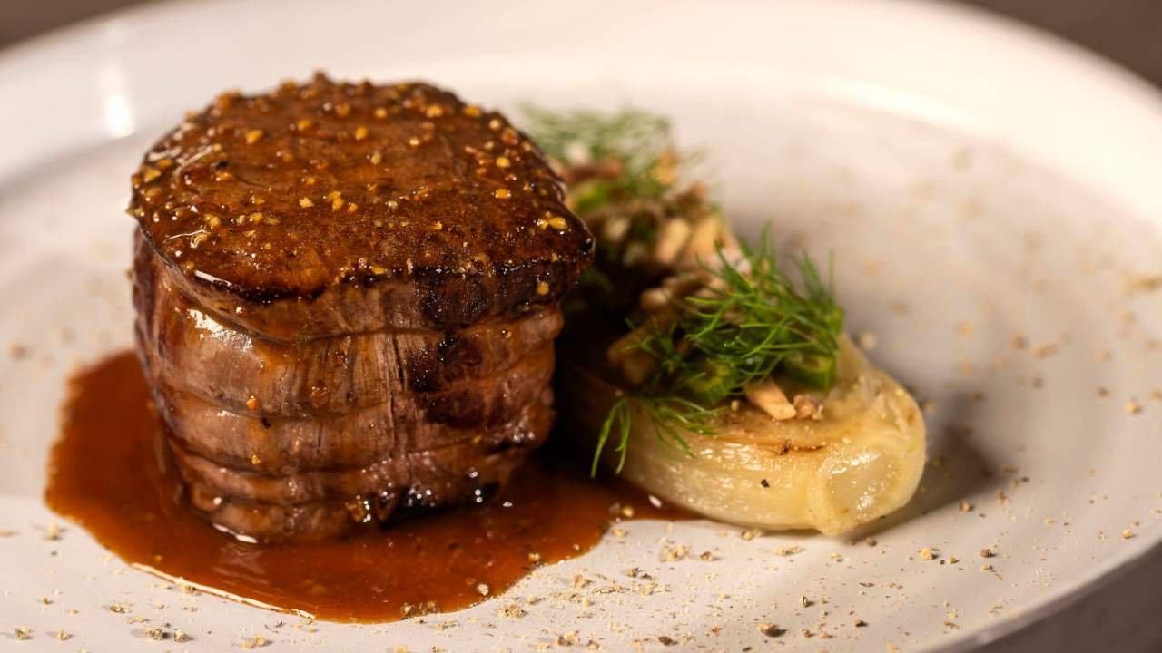 Filet de bœuf parfaitement cuit avec une sauce riche et des légumes, mettant en valeur une viande tendre et juteuse, idéale pour les recettes de faux filet de bœuf, filet de bœuf Rossini ou filet de bœuf en croûte.